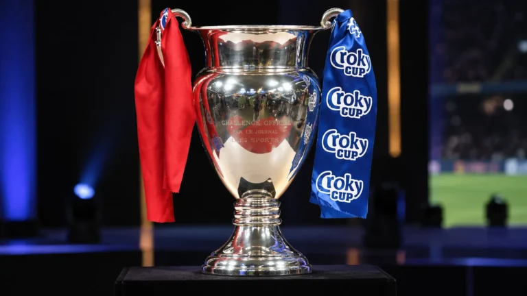 De zilveren Croky Cup-trofee met rode en blauwe linten op een donker podium.