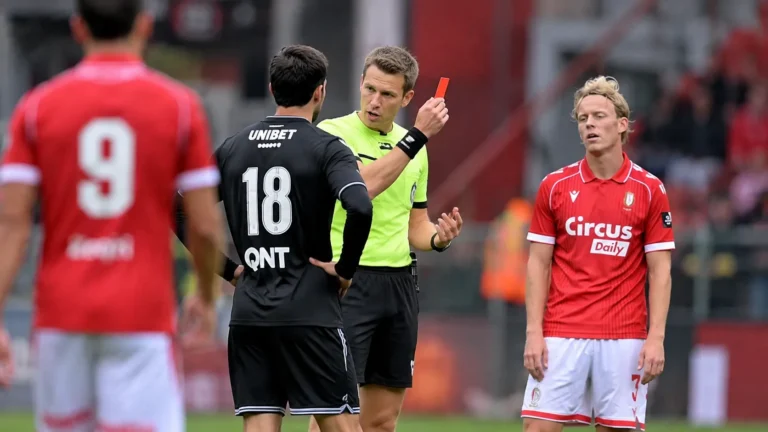 Een scheidsrechter spreekt met spelers tijdens een onderbreking in een wedstrijd van Standard.