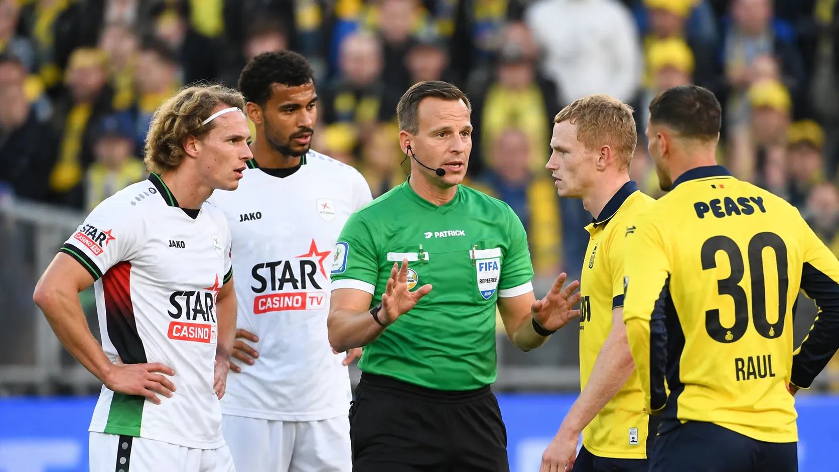 Een scheidsrechter spreekt met spelers van Union en OH Leuven tijdens een wedstrijdonderbreking.
