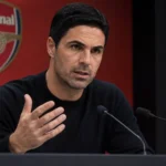 Mikel Arteta tijdens een persconferentie van Arsenal voor een vaste perswand met clubembleem.