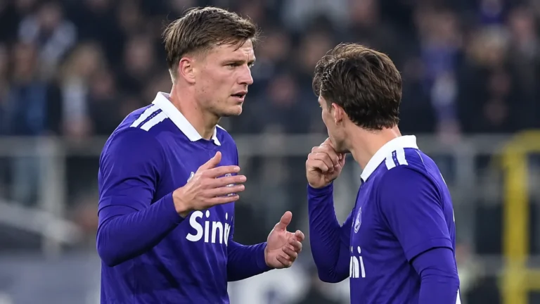 Anderlecht-spelers in blauwe wedstrijdtenues lopen samen op het veld.