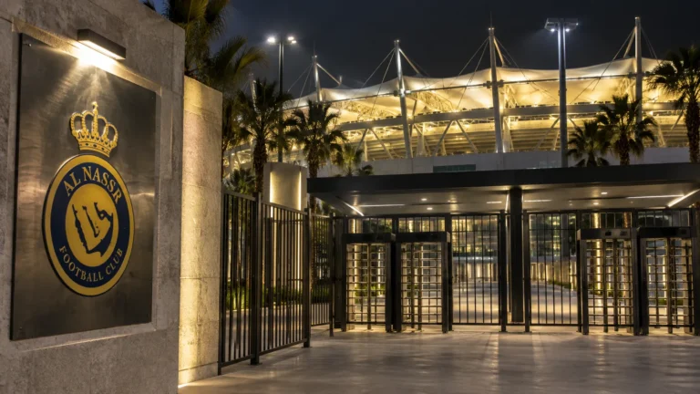 Lege verlichte stadiontoegang in Riyad met een Al Nassr-embleem op een vast metalen bord.