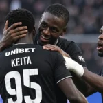 Een groep spelers van Sporting Charleroi viert samen op het veld in zwarte tenues.