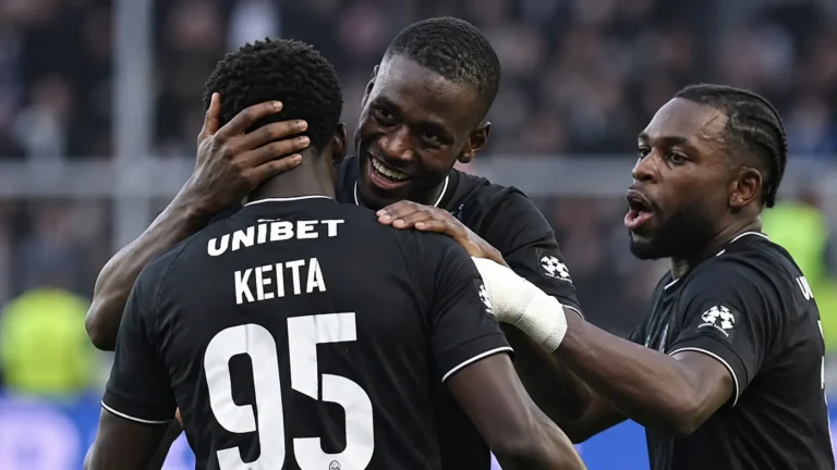 Een groep spelers van Sporting Charleroi viert samen op het veld in zwarte tenues.