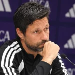 Een staflid van RSC Anderlecht tijdens een persmoment in een paarse persruimte.