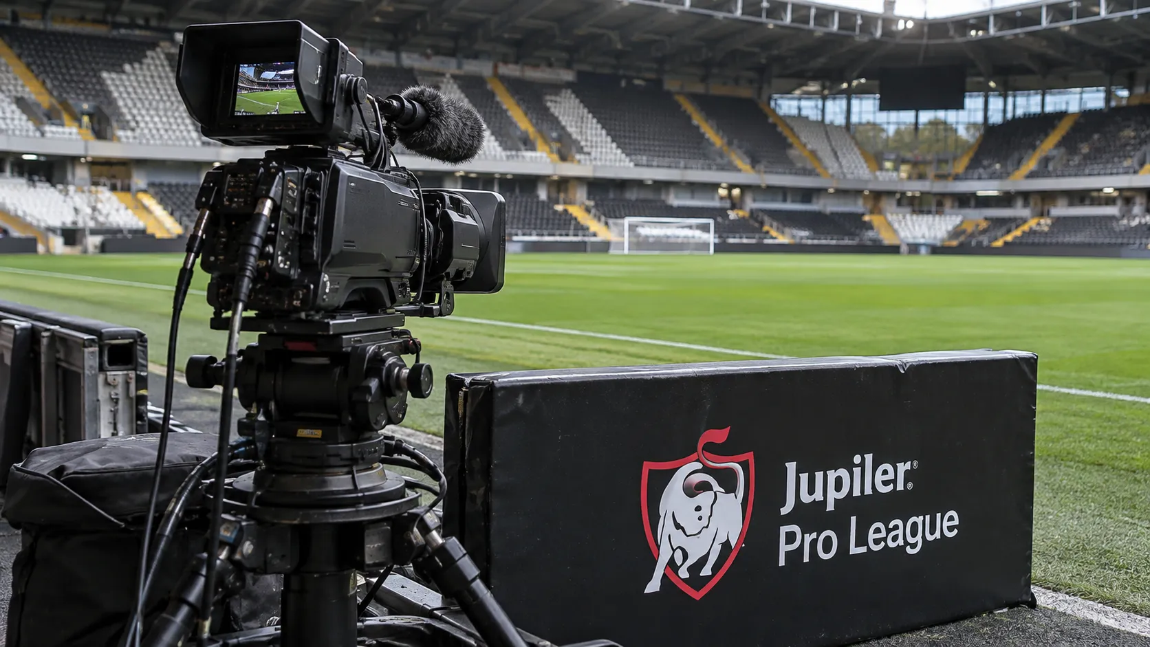 Een vaste televisiecamera naast het veld met een Jupiler Pro League-bord op de achtergrond.