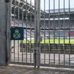 Afgesloten toegang tot een voetbalstadion in Düsseldorf met een fysiek Union-embleem op een wedstrijdbord.