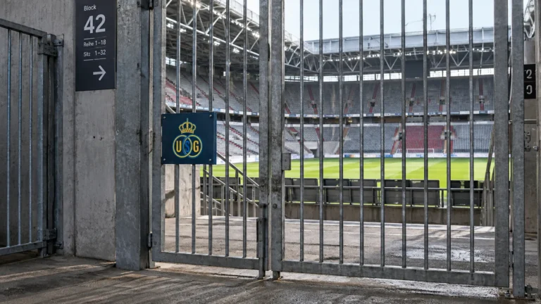 Afgesloten toegang tot een voetbalstadion in Düsseldorf met een fysiek Union-embleem op een wedstrijdbord.