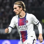 Mika Godts in PSG-shirt tijdens een wedstrijdactie onder stadionlichten.