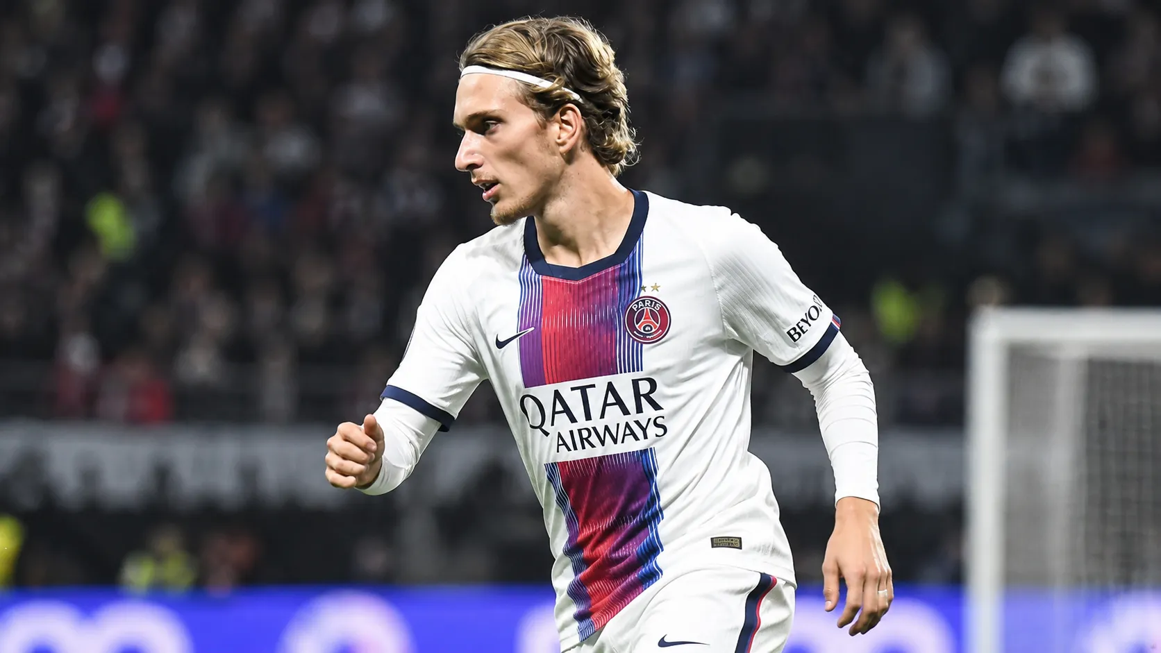 Mika Godts in PSG-shirt tijdens een wedstrijdactie onder stadionlichten.