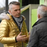 Dale Vince in gesprek met een clubvertegenwoordiger naast de tribune.