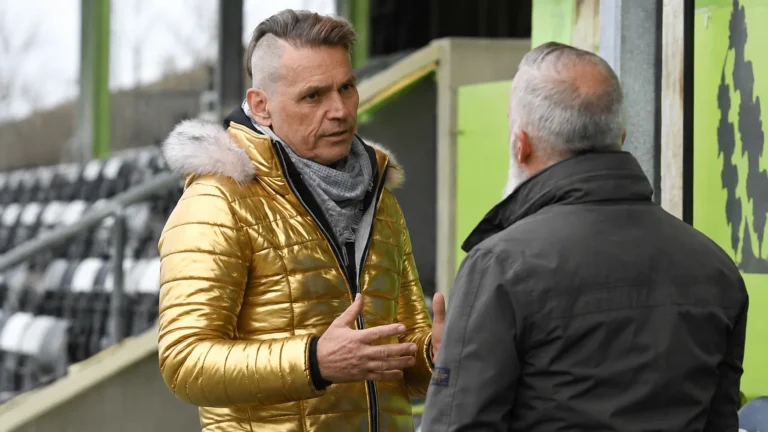 Dale Vince in gesprek met een clubvertegenwoordiger naast de tribune.
