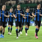 Een groep spelers van Club Brugge warmt samen op onder stadionlichten.