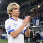 Junya Ito applaudisseert na een wedstrijd in een wit tenue met blauwe accenten.