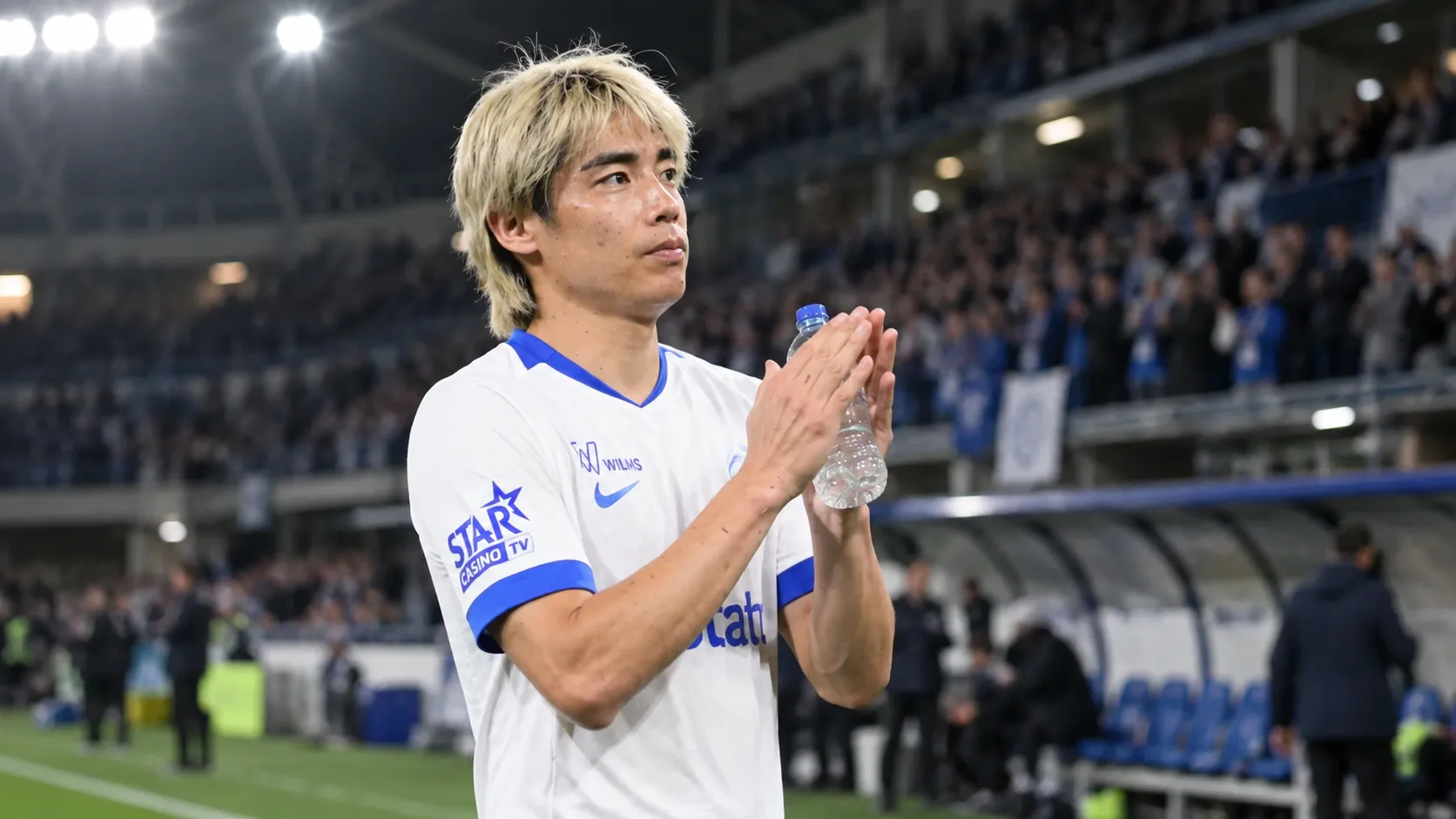 Junya Ito applaudisseert na een wedstrijd in een wit tenue met blauwe accenten.