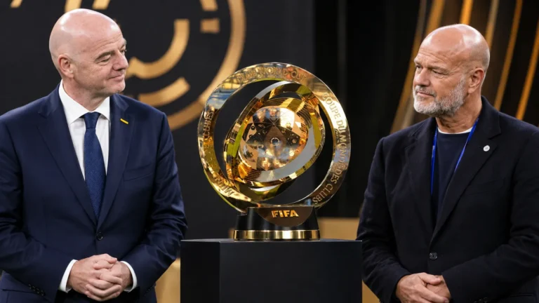 Twee voetbalofficials naast de gouden trofee van het WK voor clubs.