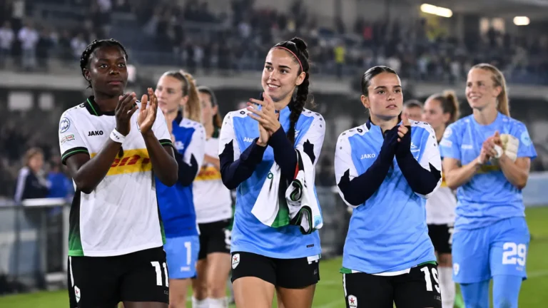 Een groep voetbalsters applaudisseert na een wedstrijd langs het veld.
