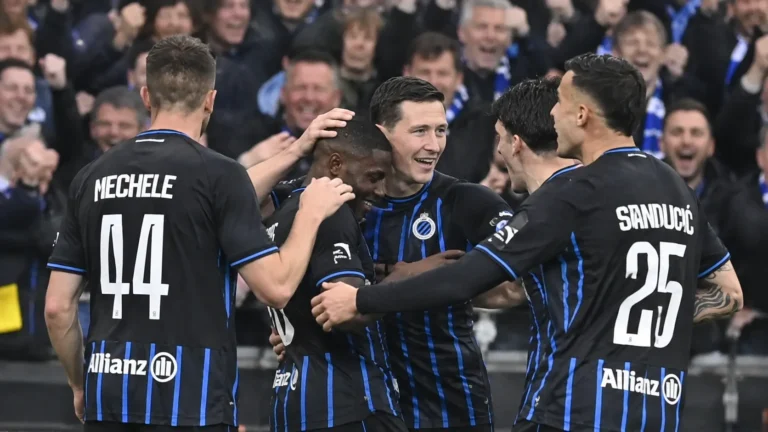 Een groep spelers in zwart-blauwe tenues viert samen voor de tribune.