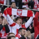 Poolse supporters vieren samen een zege in het stadion met een sjaal van de nationale ploeg.