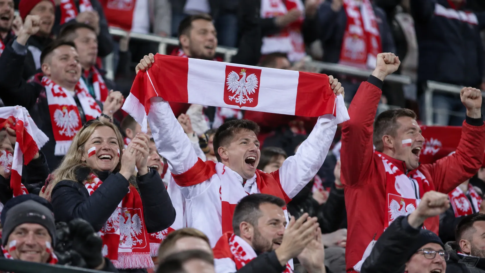 Poolse supporters vieren samen een zege in het stadion met een sjaal van de nationale ploeg.