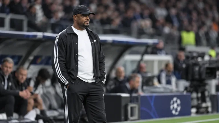 Een staflid in zwarte sportkleding staat na de wedstrijd in de technische zone.