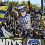 Collectieve Union-supporters met blauw-gele vlaggen op de tribune van Den Dreef.