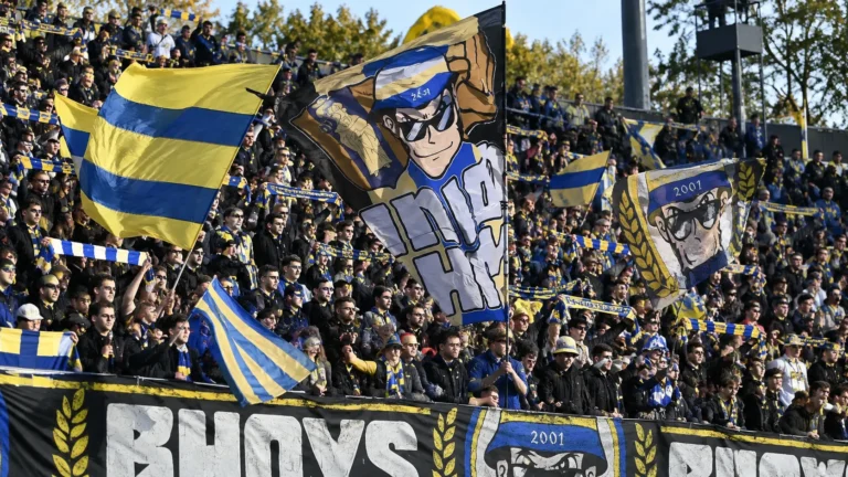 Collectieve Union-supporters met blauw-gele vlaggen op de tribune van Den Dreef.