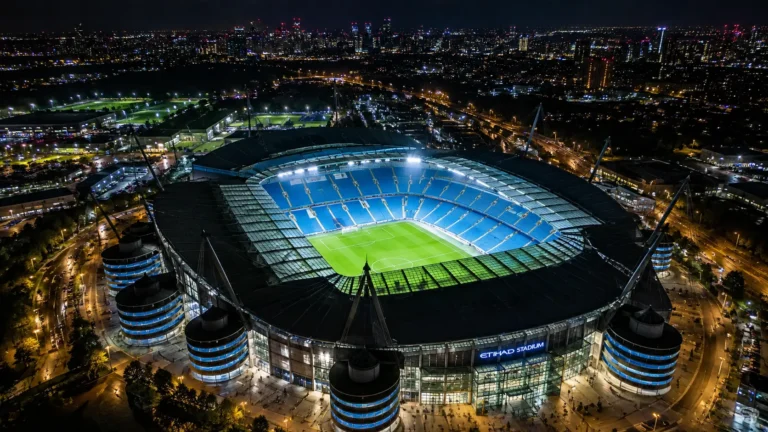 Verlicht Manchester City-stadion gezien vanuit de lucht bij nacht.