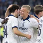 Een groep Club Brugge-spelers viert samen op het veld na een Europese uitzege.