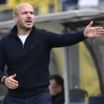 Frederic De Meyer geeft aanwijzingen langs de zijlijn, met een STVV-embleem op het paneel van de dug-out.