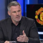 Jamie Carragher spreekt in een televisiestudio met een Manchester United-embleem op een monitor.
