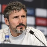 Een voetbalcoach spreekt tijdens een persconferentie.