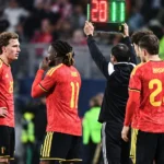 Belgische voetballers in rode tenues aan de zijlijn tijdens een interland.