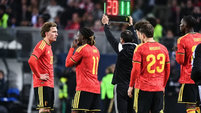 Belgische voetballers in rode tenues aan de zijlijn tijdens een interland.