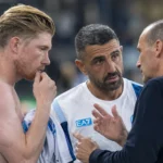 Een Napoli-speler overlegt na een wedstrijd met twee stafleden aan de zijlijn.