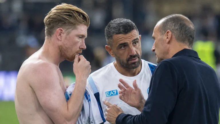 Een Napoli-speler overlegt na een wedstrijd met twee stafleden aan de zijlijn.