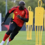 Romelu Lukaku traint in de uitrusting van de Rode Duivels tussen gele oefenpoppen.