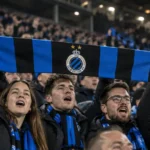 Een collectieve groep Club Brugge-supporters met een blauw-zwarte sjaal in de tribune.