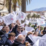 Een groep supporters zwaait met witte vlaggen op de Riva-boulevard in Split.