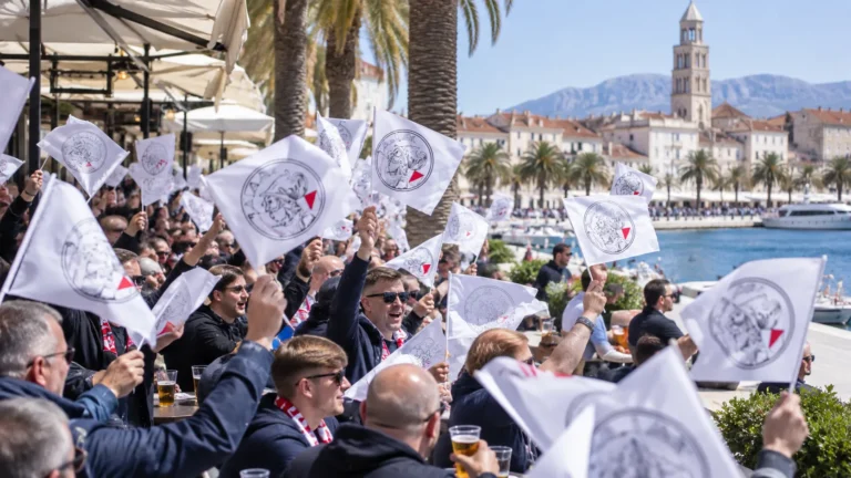 Een groep supporters zwaait met witte vlaggen op de Riva-boulevard in Split.