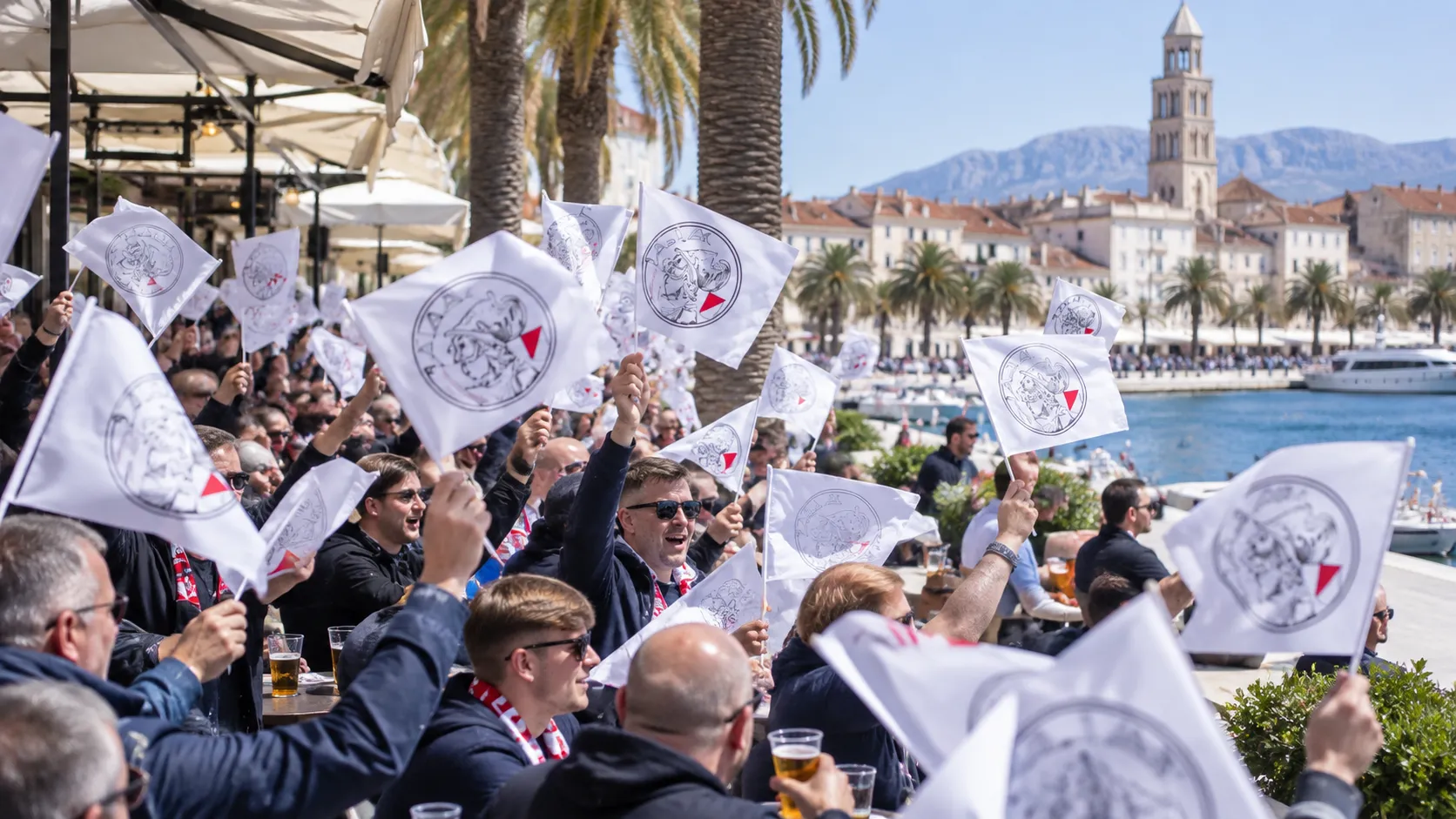 Een groep supporters zwaait met witte vlaggen op de Riva-boulevard in Split.