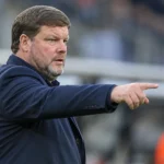 Hein Vanhaezebrouck kijkt geconcentreerd naar het veld in een stadionomgeving.
