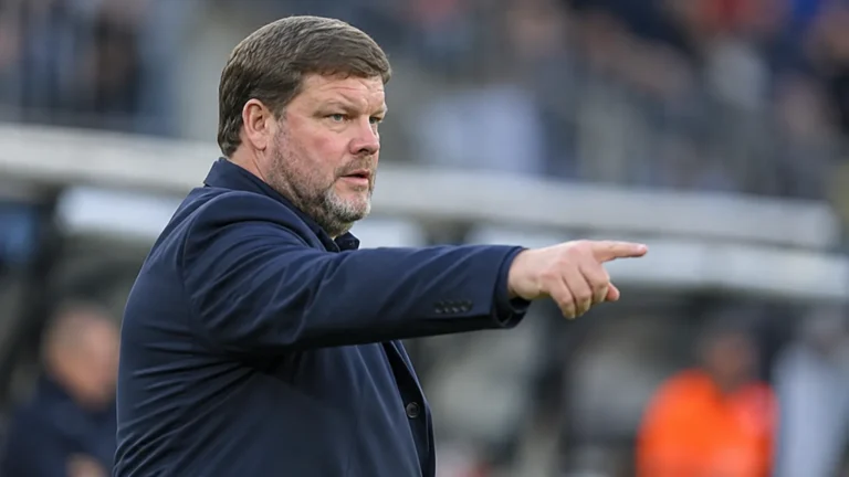 Hein Vanhaezebrouck kijkt geconcentreerd naar het veld in een stadionomgeving.