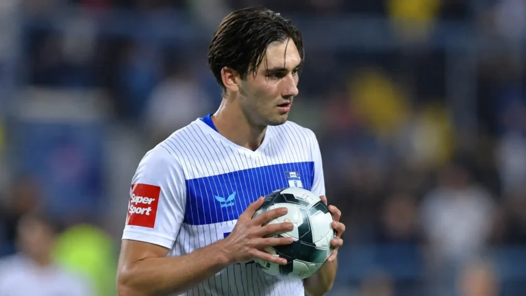 Dion Beljo in een wit shirt met blauwe borstband terwijl hij een bal vasthoudt.