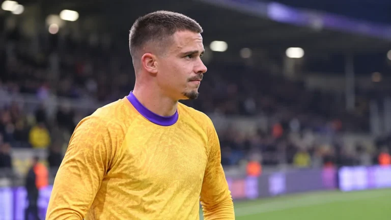 Leander Dendoncker in een geel voetbalshirt in een stadionomgeving.