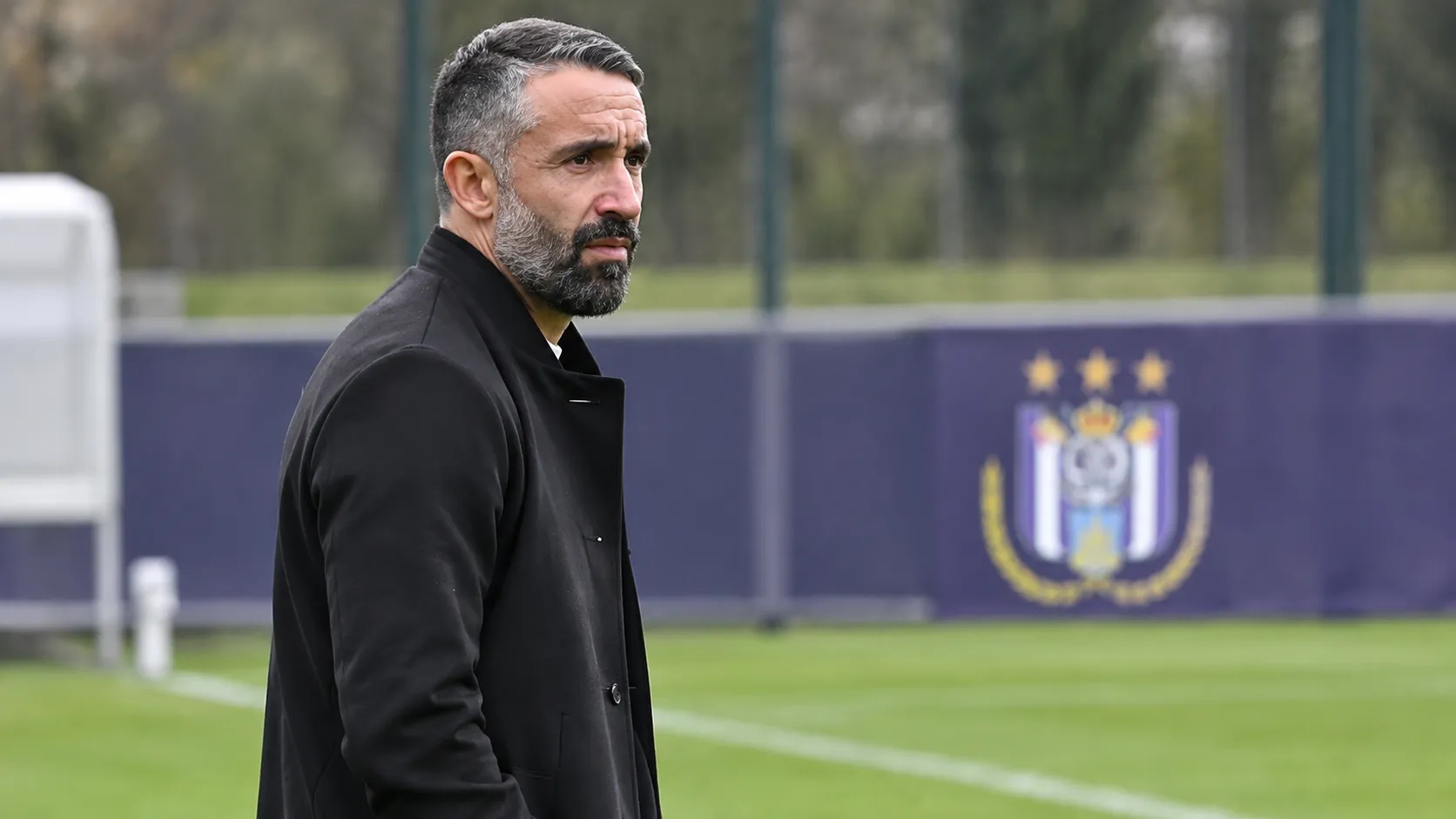 Jérémy Taravel kijkt aandachtig vanaf de zijlijn van een trainingsveld van Anderlecht.
