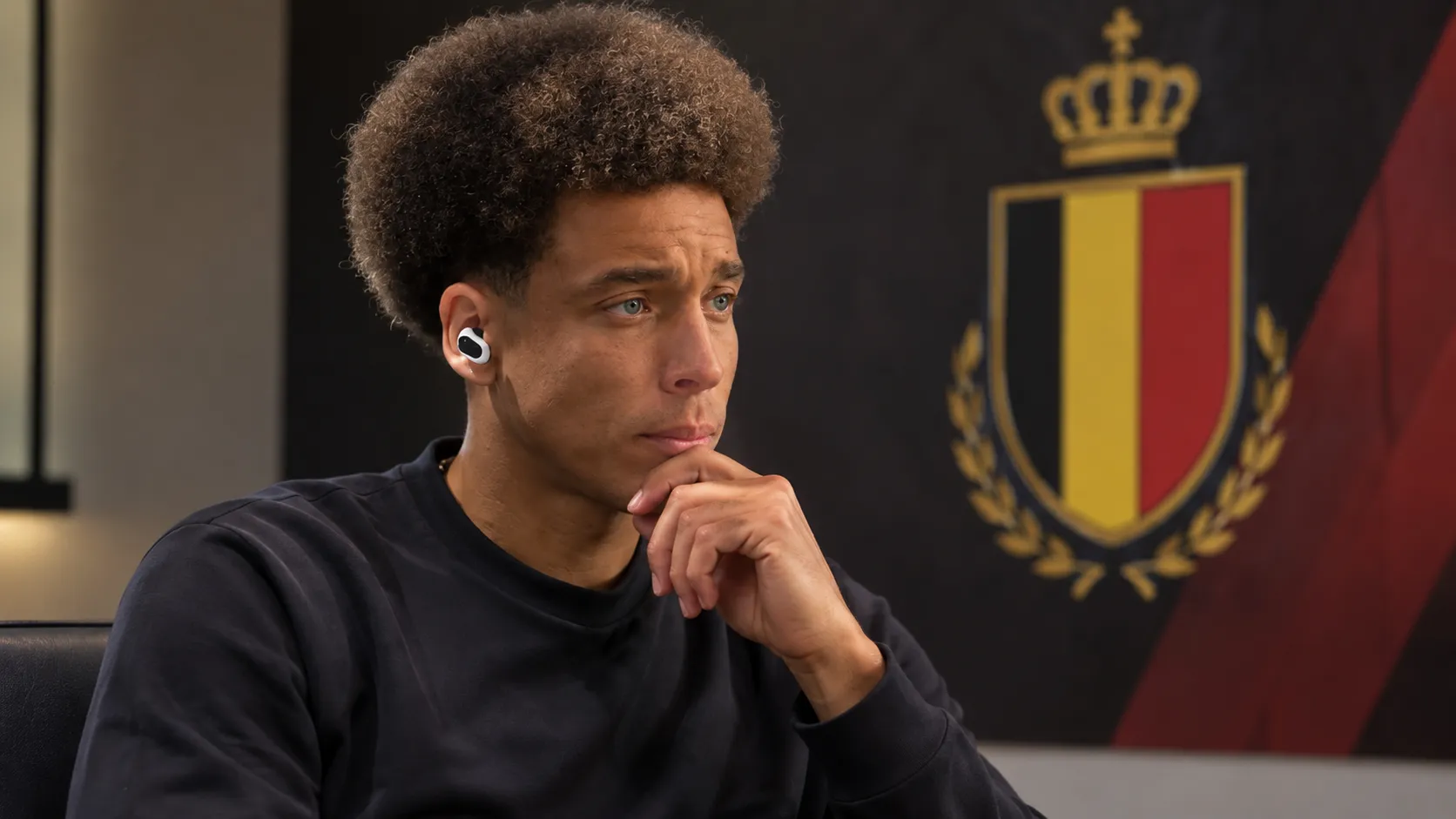 Axel Witsel tijdens een rustig interview in een neutrale mediaruimte met een Rode Duivels-embleem op een wandpaneel.