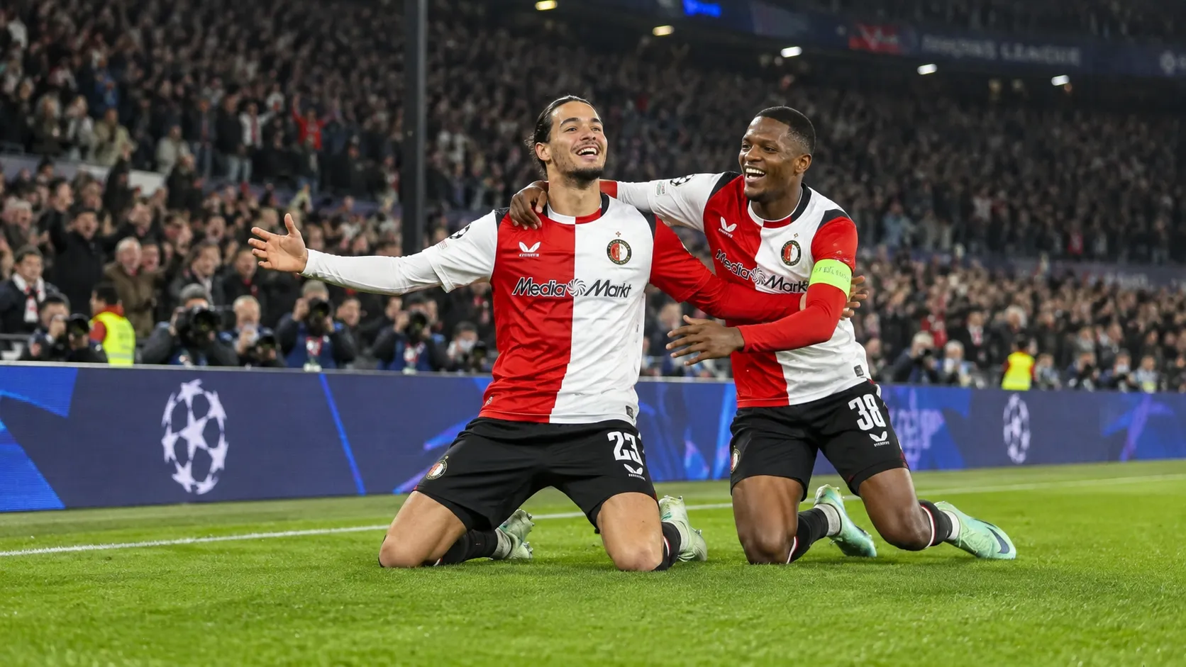 Twee Feyenoord-spelers vieren samen op het veld tijdens een Champions League-wedstrijd.